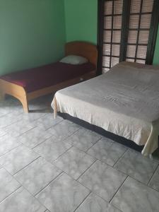 马蒂尼奥斯Kitnet em Matinhos PR Balneário Riviera的卧室配有一张床,在瓷砖地板上设有长凳