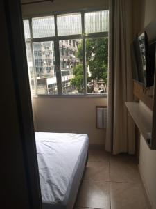 尼泰罗伊Loft Aconchegante no Centro de Niterói!!的卧室在窗户前配有一张床