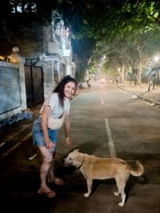 科钦Santa Maria Hostel, Fort Kochi的站在街上狗旁边的女人