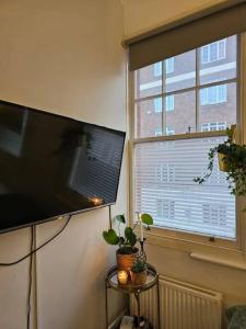 伦敦Beautiful and spacious flat的窗户旁墙上的平面电视