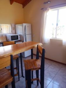 圣卡洛斯-德巴里洛切El Llanqui的厨房配有木桌、椅子和冰箱。