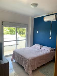 弗洛里亚诺波利斯Residencial Ametista - 250 metros do mar的一间卧室配有一张蓝色墙壁和窗户的床