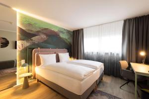 慕尼黑慕尼黑瑞拉诺酒店的卧室配有一张床,墙上挂有绘画作品