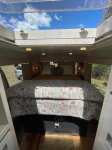 FaradayBUS - Tiny home - 1980s classic with off grid elegance的露营车后面的一张床位