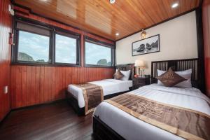下龙湾Ruby Cruise的配有木墙和窗户的客房内的两张床