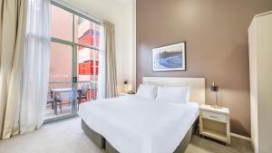 悉尼Oaks Sydney Goldsbrough Suites的卧室设有一张白色大床和一扇窗户。