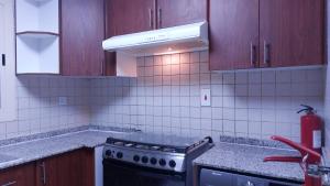 迪拜PRIVATE ROOM FOR BUSINESS EXECUTIVES BY MAUON TOURISM的厨房配有木制橱柜和炉灶烤箱。