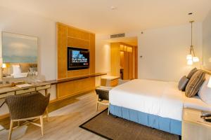 邦劳Modala Beach Resort的酒店客房配有一张床、一张书桌和一台电视。