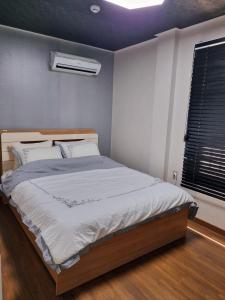 安东市Food House的卧室配有一张带白色床单的大床和窗户。