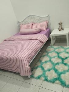阿罗士打Asmar's Homestay Alor Setar的一张带粉色紫色毯子和桌子的床