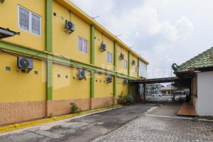 NegarasakaHomestay Hj Suharti Natar Lampung RedPartner的黄色和绿色的建筑,有街道