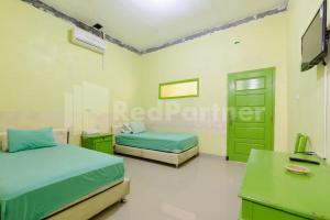 NegarasakaHomestay Hj Suharti Natar Lampung RedPartner的一间卧室配有两张床、一张桌子和一台电视。