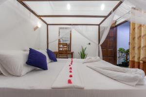 阿鲁甘湾Chimaca Bay Hotel的一张大白色的床,上面有红丝带