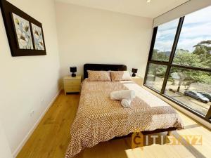 堪培拉Lavish in Lyneham - 2BD 1Bth Apt的一间卧室设有一张床和一个大窗户