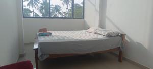 阿勒皮Beach vibe hostel的窗户客房内的小床