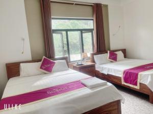 峰牙Starlet Hotel Phong Nha的带窗户的客房内的两张床