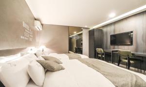 首尔Jamsil 2.4 Hotel的卧室配有一张白色大床和电视。
