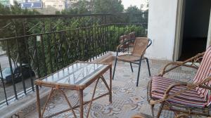 开罗Heliopolis Almazah apartment的阳台配有三把椅子和玻璃桌