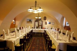 多瑙河畔海恩堡Gasthof zum Goldenen Anker的一间长餐厅,配有白色的桌子和椅子