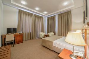 敖德萨Alarus Luxe Hotel的酒店客房配有一张床、一张书桌和一台电视。