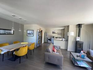 阿拉东Charmante Maison 400m du Golfe - Jacuzzi的客厅和配有桌子及黄色椅子的用餐室