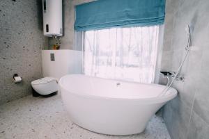 赫梅利尼克Rado Hotel Spa的带窗户的浴室内的白色浴缸