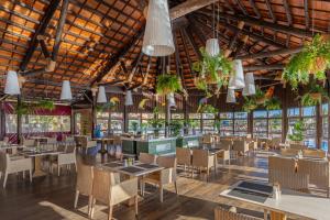 卡勒达德福斯特Elba Sara Beach & Golf Resort的一间设有桌椅和盆栽的餐厅