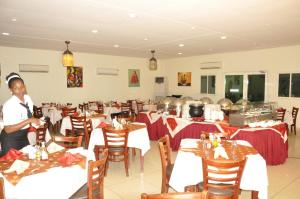 朱巴Grand Hotel Juba的中间有餐桌和女人的餐厅
