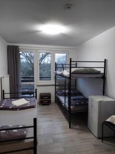 罗兹Ośrodek Wypoczynkowo-Hotelowy PRZĄŚNICZKA的带三张双层床和两扇窗户的房间