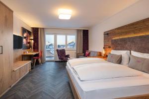 上陶恩Hotel Zehnerkar & Hotel Obertauern的酒店客房设有一张大床和一张书桌。