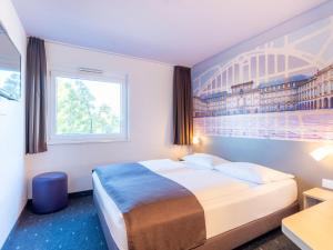 曼海姆B&B Hotel Mannheim的酒店客房设有一张床,墙上挂有绘画作品