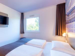 曼海姆B&B Hotel Mannheim的酒店客房设有床和窗户。