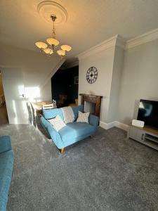 MytholmroydLovely home with a river view的客厅配有蓝色的沙发和墙上的时钟