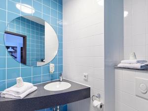 明斯特B&B HOTEL Münster Hafen的蓝色瓷砖浴室设有水槽和镜子