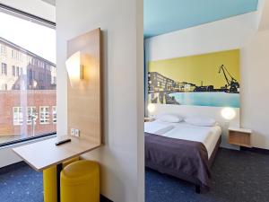 明斯特B&B HOTEL Münster Hafen的配有一张床、一张书桌和一扇窗户的酒店客房