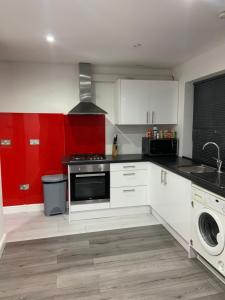 海维康Inviting 2-Bed fully Furnished House-High Wycombe的厨房配有白色橱柜和红色墙壁