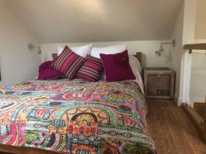 艾尔斯伯里The Bike Shed, Near Brill的一间卧室配有一张带彩色毯子和枕头的床。
