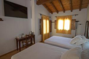 夸科斯德尤斯特亚巴迪亚德乌斯特乡村酒店 的一间卧室配有两张床、一张桌子和一台电视。