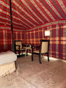 Al WāşilHamood desert local camp的一间卧室配有一张床、两把椅子和一张桌子