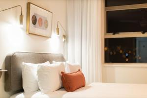 开普敦Habitat Aparthotel by Totalstay的卧室配有带白色枕头的床和窗户。