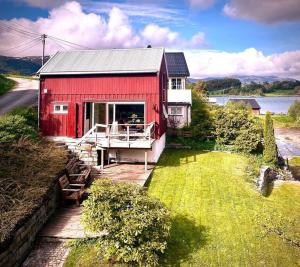 Hus ved Valsøyfjorden的湖边的红色房子,有甲板