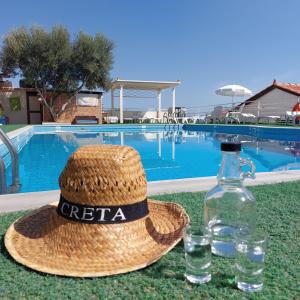 赫索尼索斯美景别墅的游泳池畔的草帽和一瓶水