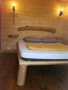 圣皮索内维尔camping Manex的木制客房内的一张小床,配有两个枕头