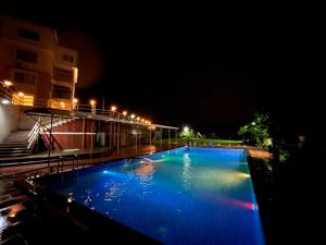 潘奇加尼Ivy Park Resort的一座大型蓝色游泳池,晚上与大楼相连