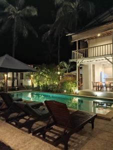 吉利特拉旺安White Coconut Resort的夜间游泳池,配有两把椅子和一把遮阳伞