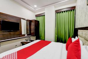 Keonjhargarhhotel adhunik palace的一间卧室配有一张带红色枕头的床和电视。