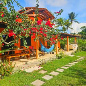 库穆鲁沙蒂巴Villa Mar a Vista - Suite Alamanda的一座带吊床和红色鲜花的房子