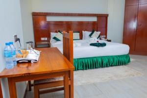 阿鲁沙Kerama Silent Lodge的酒店客房配有一张床和一张桌子,桌子上装有四面 ⁇ 