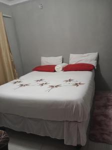 马翁Partulaka Rest Inn的一间卧室配有带白色床单和红色枕头的床。