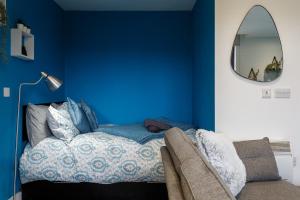 谢菲尔德Brand New Studio Apartment in Sheffield的一间蓝色卧室,配有一张床和镜子